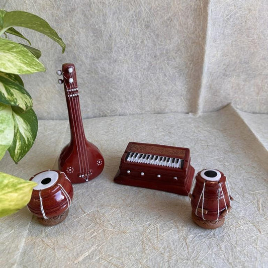 Handcrafted miniature set of Indian musical instruments, including a Veena, Harmonium, and two Mridangams, for Navarathri Golu displays.