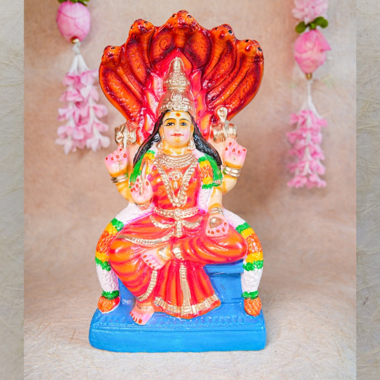 Handcrafted Navarathri Golu doll of Goddess Karumari Amman seated under a serpent canopy, adorned with vibrant red, blue, and gold detailing.