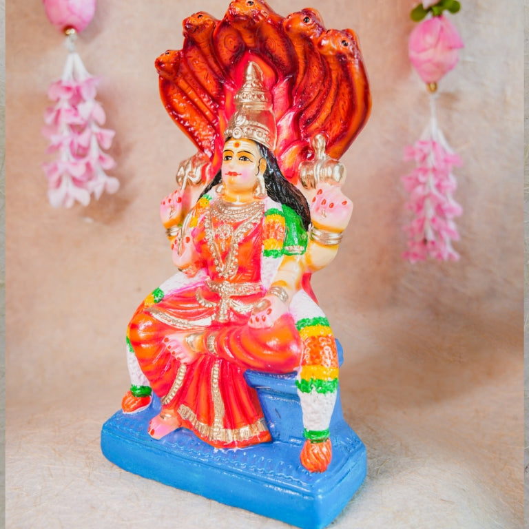 Handcrafted Navarathri Golu doll of Goddess Karumari Amman seated under a serpent canopy, adorned with vibrant red, blue, and gold detailing.