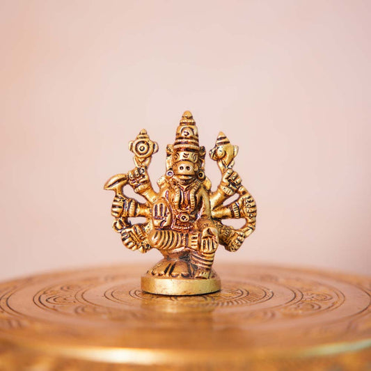 Brass Varahi idol with intricate detailing, showcasing the eight-armed form of the goddess, placed on a decorative surface.