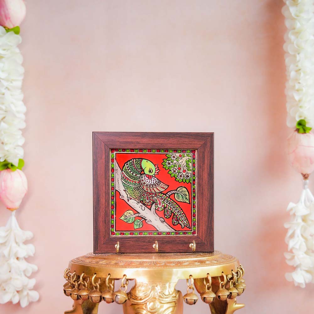 Decorative keyholder featuring a hand-painted parrot design on a vibrant Red background, framed with dark wood, and fitted with key hooks.