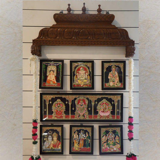 Aalayam carved gopuram frame in Vaagi wood with a teakwood finish, adorned with Tanjore paintings and floral garlands.