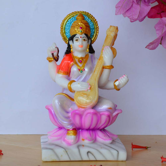 Handcrafted Saraswati Idol with marble finish, seated on a lotus, holding a veena, and adorned with vibrant colors.