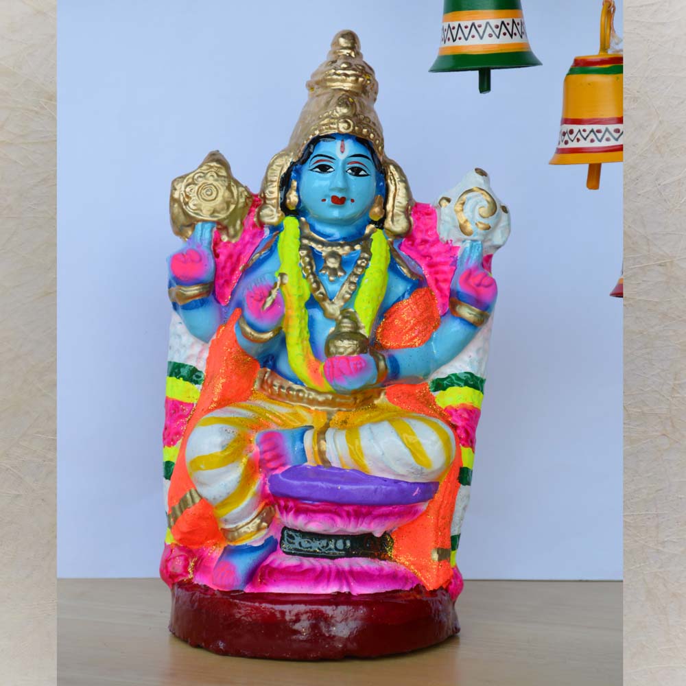 Handcrafted Navaratri Dhanvantari Golu doll featuring the God of Ayurveda seated in a vibrant pose, painted with rich blue, gold, and orange tones against a decorative background.