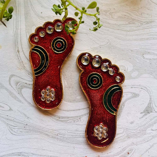 Medium-sized decorative Paatham footprints with red and green enamel and sparkling stones, displayed on a white textured background.