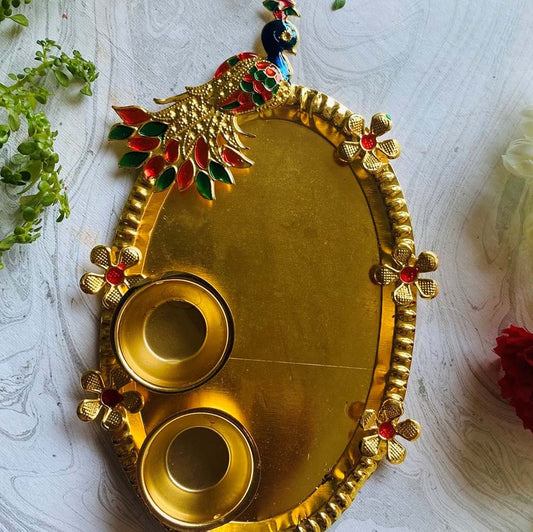 Gold peacock-themed Pooja Thali with 2 cups, featuring red and green enamel detailing, floral accents, and a polished finish, displayed on a white textured background.