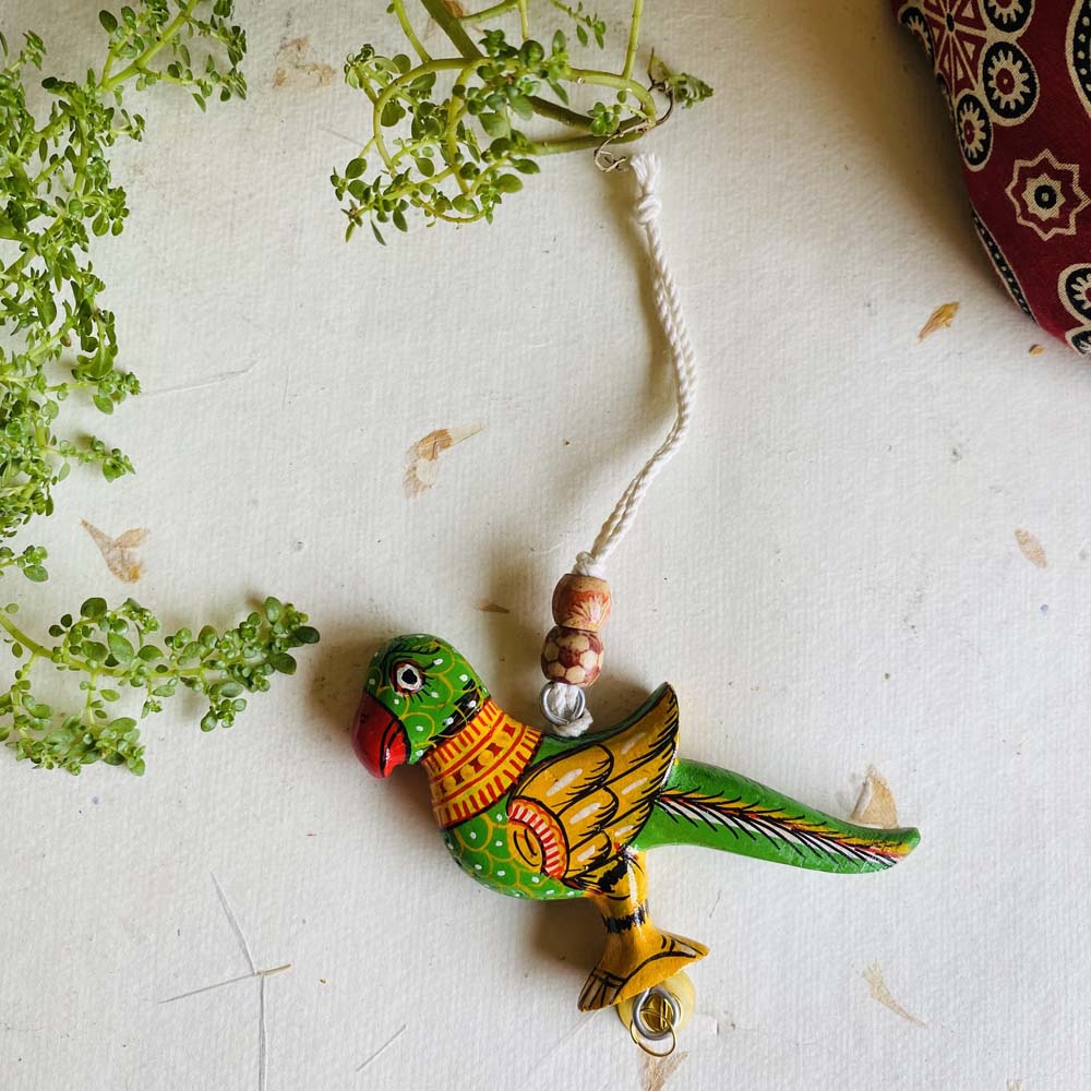 Handcrafted green wooden hanging parrot decor with traditional hand-painted designs, beads, and a decorative bell.