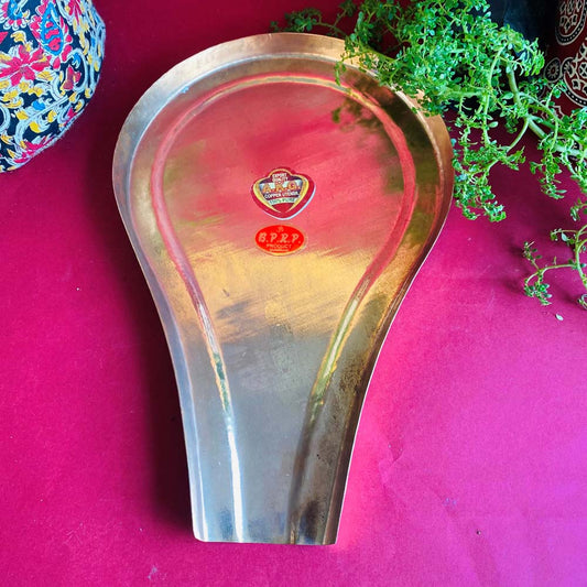 Traditional copper Abhishekam tray with a polished finish, displayed on a vibrant red background with decorative elements.