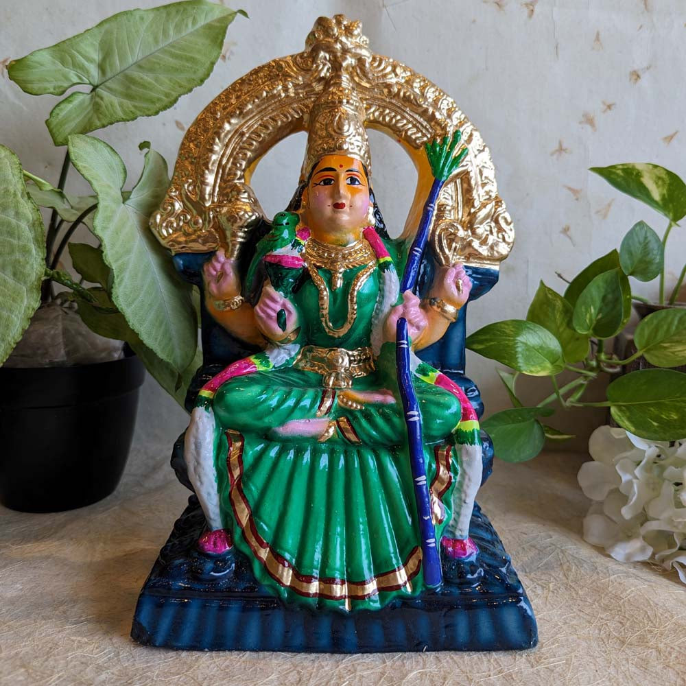 Handcrafted Kamakshi Amman figurine seated on a golden throne with vibrant green attire, a parrot, and detailed embellishments.