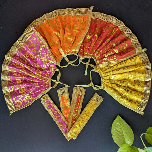 Traditional Devi skirts in vibrant brocade fabric with gold motifs and borders, displayed in red, orange, pink, and yellow on a black background with green leaves.