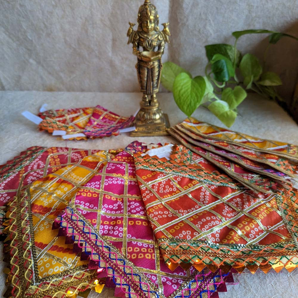 Traditional Sai Vastra set with Bandhani design and zari borders in vibrant colors, displayed with a brass Sai Baba idol.