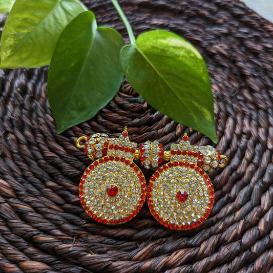 Gold-plated Small Thali Ornament with red and white stones placed on a woven mat with green leaves in the background.