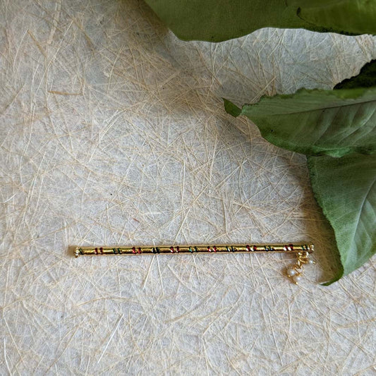 A decorative Krishna flute with vibrant stripes, golden detailing, and pearl accents, displayed against a textured background.