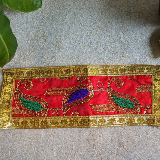 Traditional red embroidered Aasan with golden borders and vibrant green and blue peacock motifs, measuring 9 x 3.