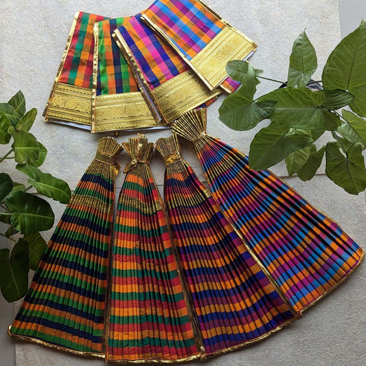 A traditional multicolored checked Devi skirt with golden zari borders, displayed alongside fresh green indoor plants, highlighting its intricate detailing and vibrant colors.