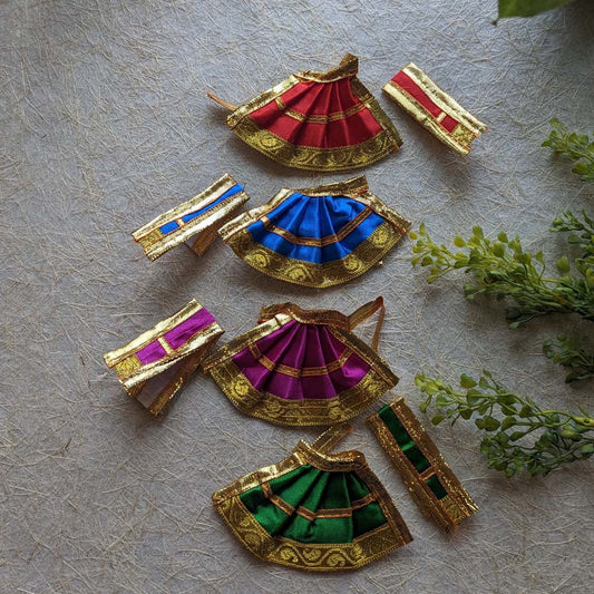 Blue Devi skirt with golden zari borders and an assortment of red, magenta, and green skirts for deity decoration.