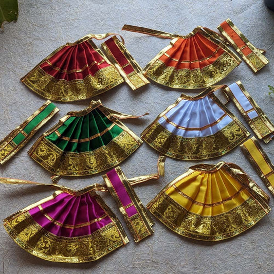 Mini Devi skirts in vibrant colors including red, orange, green, white, yellow, and purple with intricate gold borders, arranged neatly in a set.