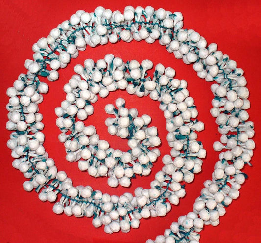 Intricately handcrafted artificial Malli paper garland in white with green accents, displayed in a spiral arrangement against a red background.