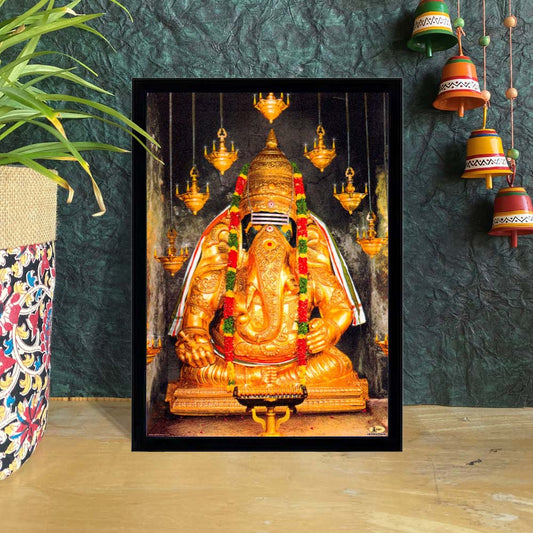 Karpagha Vinayagar golden idol framed art with lamps and floral garlands.