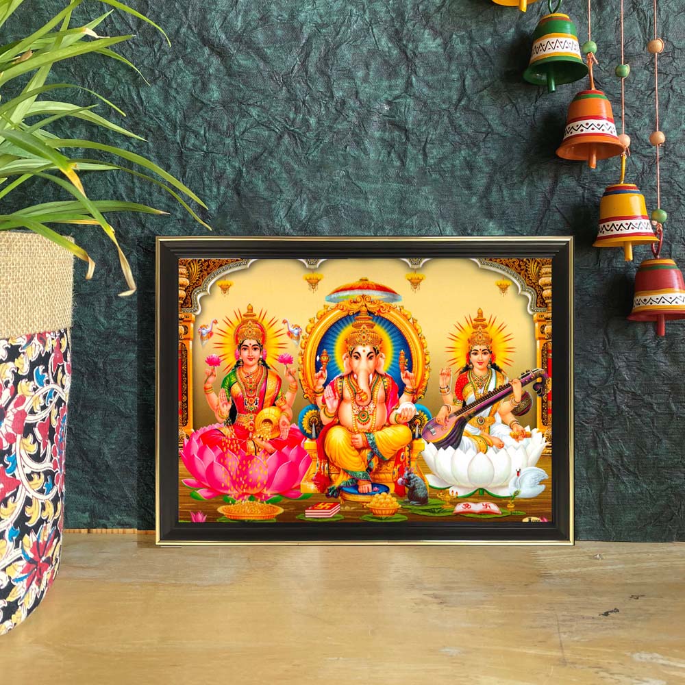 Lakshmi, Ganesha, and Saraswati artwork featuring the divine trio seated on pink and white lotuses with a temple-inspired golden backdrop.