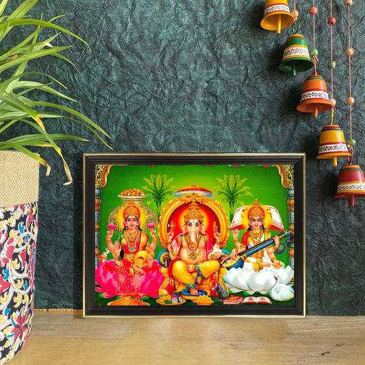 Lakshmi, Ganesha, and Saraswati artwork with the divine trio seated on vibrant pink and white lotuses against a green backdrop, adorned with gold details.